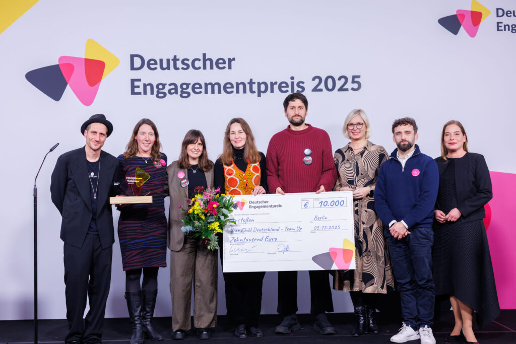 Preisträger und Preisträgerinnen auf der Bühne mit einem Scheck in der Hand